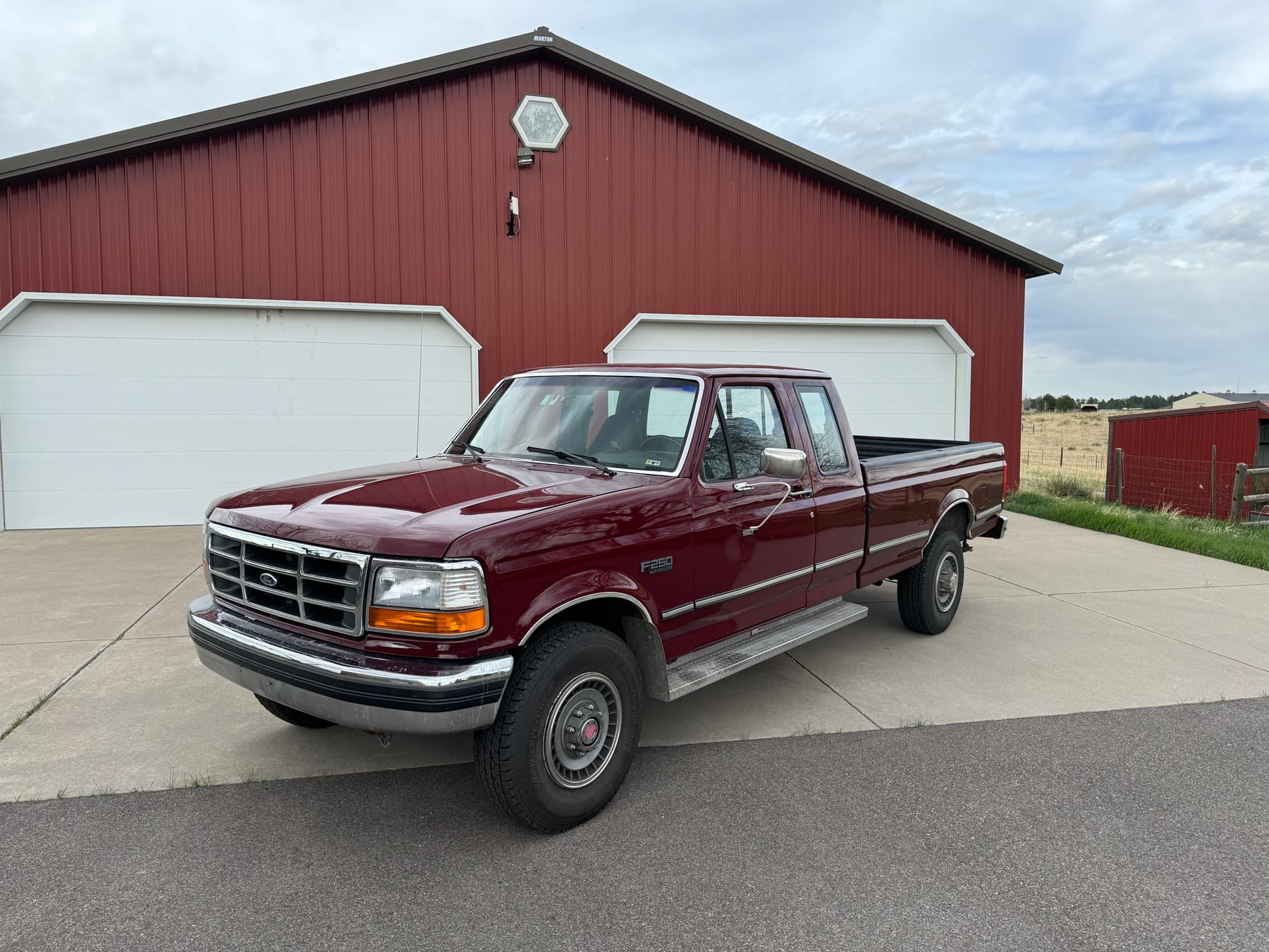 The ranch's 1993 Ford F250, dark red, parked in front of the barn